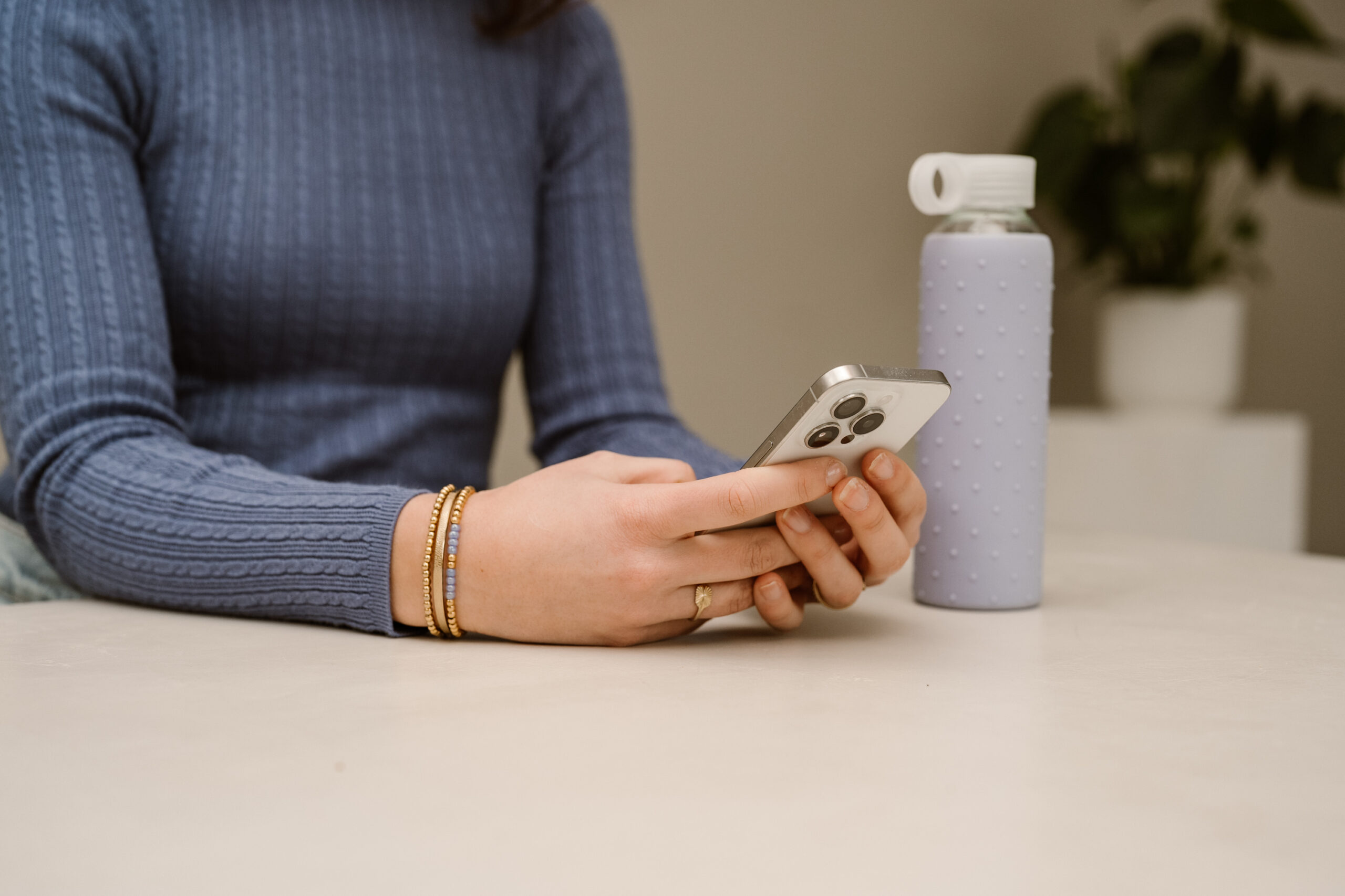 persoon aan tafel met een telefoon in de hand.