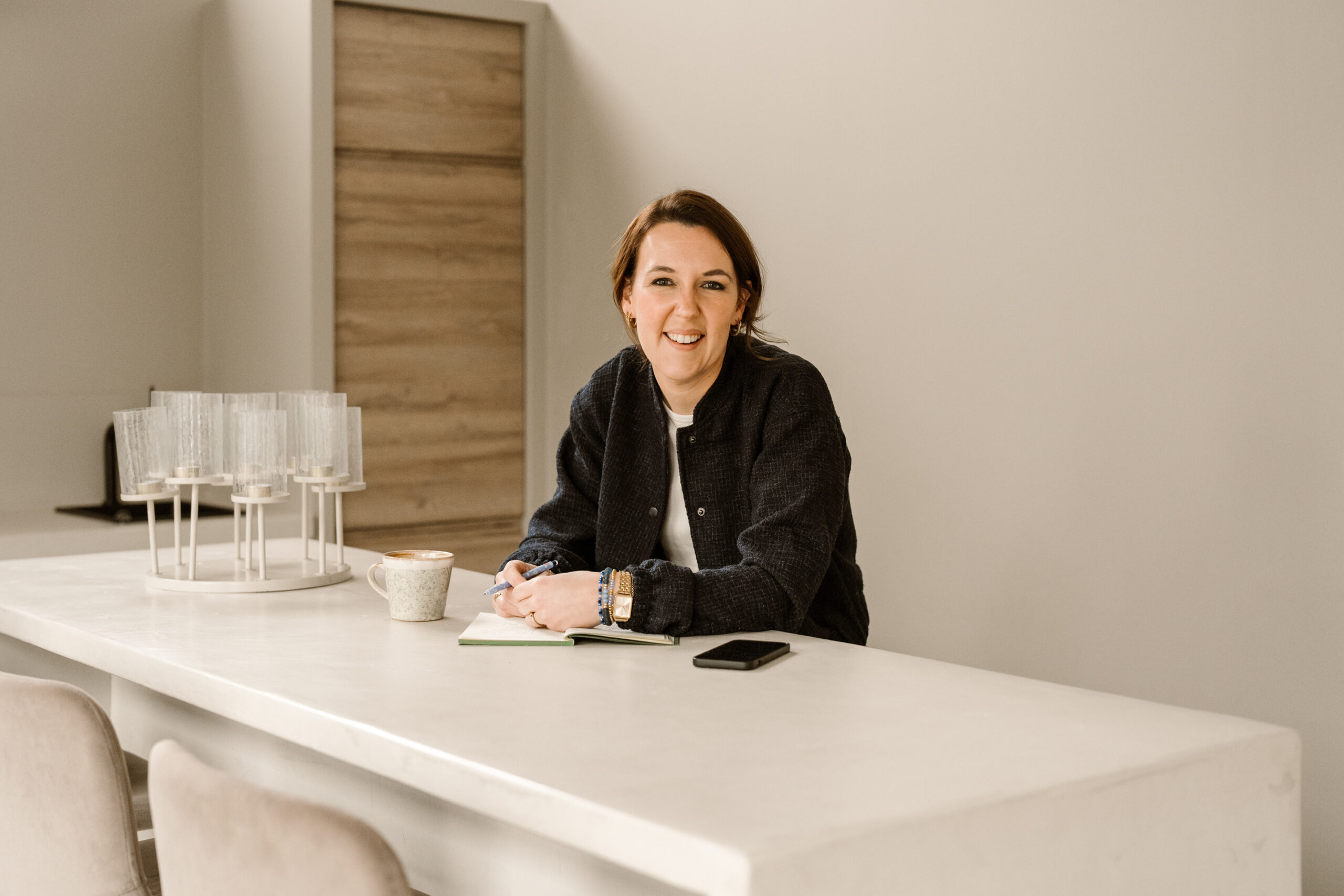 Eigenaresse Copybright aan een hoge tafel met mobiel en kopje koffie.